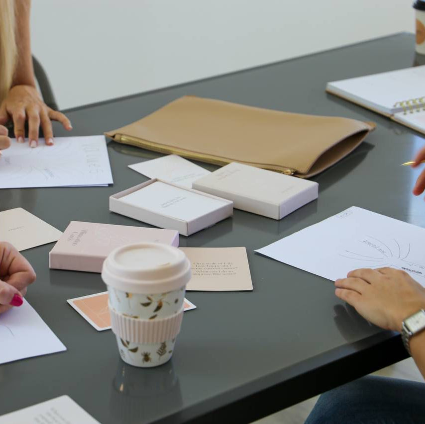 People working at a table with notebooks, pens, and coffee cups with their Analog Bag